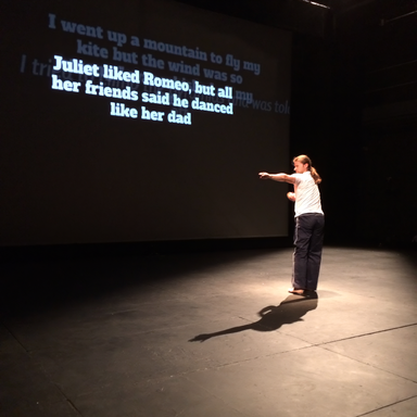 Dancer on stage working on a story projected behind them